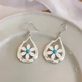Detailed shot of hollow waterdrop earrings with white flower and blue stone - Ear Hook Earrings / Pair / Silver