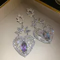Primer plano de pendientes de corazón grandes con brillantes pedrería y cristales. - Estilo Flor Corazón (HE34086) / Plateado (Color AB)
