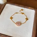Dettaglio macro di un bracciale placcato oro 18 carati con ciondolo a fiore rosa - Bracciale / Oro-Rosa