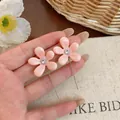 Primer plano de pendientes de flor de resina rosa con circón y cadenas de plata - Rosa