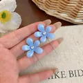 Primer plano de los pendientes de flor de resina azul con brillantes y cadena larga. - Azul