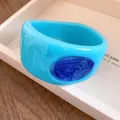 Detailopname van een blauwe harsarmband met donkerblauwe emaille details - Hemelblauwe Hars Sterrenhemel Textuur Stijl / Hemelsblauw