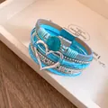 Detailopname van een blauwe meerlaagse boho-wikkelarmband met een zilveren hartje - Meerlaagse Gevlochten Hart Hanger Stijl / Blauw