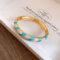 Detailweergave van een vergulde armband met turkoois en roze emaille golfpatroon - Gouden Frame Golf Emaille Stijl / Wit-Cyaan