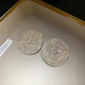 Vista macro de pendientes circulares con diamantes brillantes y aguja de plata. - Dorado