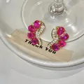 Close-up view of elegant red teardrop earrings featuring a curved golden design. - Gold Base Teardrop Style (HE33288) / Rose Red