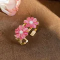 Detailed view of gold cuff bracelet featuring two pink enamel daisies with pearl centers - Pink