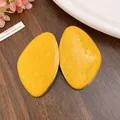 Primo piano di orecchini geometrici irregolari in smalto giallo con bordi dorati su legno - Giallo
