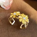 Macro view of an elegant yellow daisy bangle bracelet with gold leaf and pearl accents - Yellow