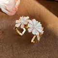 Detailed close-up view of a golden daisy cuff bracelet with white petals and pearls - Beige