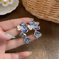 Detailed view of blue and white enamel floral cluster earrings featuring central crystals - Dark Blue