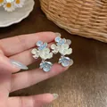 Close-up detail of floral drop earrings with colorful enamel and sparkling rhinestones. - Light Blue