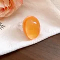 Close-up view of a vintage minimalist orange oval resin ring with a transparent band - Orange