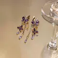 Vista macro dettagliata di orecchini a farfalla viola con strass scintillanti e placcatura in oro giallo - Stile Farfalla con Nappe (HE32255) / Oro-Viola