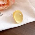 Detailed view of a vintage yellow oval resin ring with a transparent band on white cloth. - Yellow