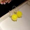Macro view showing the yellow textured bead and transparent flower cap of these earrings. - Hook Style / Yellow