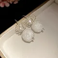 Detailed close-up of crystal flower dangle earrings with textured round bead pendants - Hook Style / White