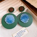 Dettaglio macro di orecchini vintage con rosa in resina blu su base tonda verde scuro - Stile Pendente a Fiore Vintage / Verde & Blu