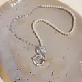 Macro view of elegant zircon pearl beaded necklace with star pendant on ceramic plate - Silver
