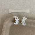 Dettaglio di eleganti orecchini a fiore a forma di C in argento con delicate perle bianche - Perno in argento-Bianco