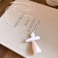 Close-up of minimalist resin pendant necklace with white leather cord on linen book - White