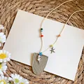 Detalle de cuentas coloridas y colgantes de estrella de mar en un collar estilo playero - Blanco Roto