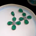 Detailed view of green resin flower earrings with silver-tone metal accents on a plate. - Earrings / Green
