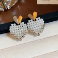 Close-up of elegant heart-shaped stud earrings featuring small white pearls and gold accents. - Gold (HE31759)