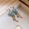 Detailed view of vintage blue beaded earrings with pearls and amber stones in a jewelry box - Gold-Blue-Coffee