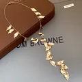 Macro detail showing the exquisite vintage textured finish of this gold leaf tassel necklace. - Gold