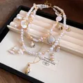 Detailed close-up of a vintage double-layered necklace with pearls and shell pendants - Champagne