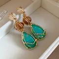 Detailed macro view of vintage teardrop resin earrings featuring textured gold frames - Green
