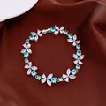 Detailed macro shot of flower bracelet featuring sparkling blue and white cubic zirconia. - Flower Open Bracelet / Silver-Blue