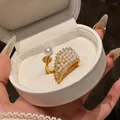 Close-up of elegant gold wing ring with embedded pearls and sparkling zircons - Gold