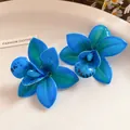 Primo piano di orecchini a lobo a forma di orchidea blu vibrante con finitura in resina. - Stile Orchidea (HE31628) / Blu