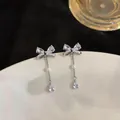 Elegant silver bow earrings with sparkling zircons and white pearl drop detail in SKU view - Bow Knot Tassel Style (HE32947) / Silver (Silver Pin)