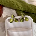 Detailansicht der grünen Emaille-Ohrringe mit fein texturierten silbernen Blütenblättern. - Silbernadel / Silber-Grün