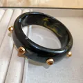 Gros plan d'un bracelet jonc rétro en résine avec clous ambrés sur plateau à bijoux - Noir