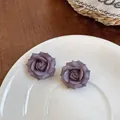 Primo piano di orecchini a forma di rosa viola su un piatto di ceramica bianca - Viola