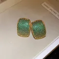 Close-up detail of vintage gold-plated earrings with green zircon pavé - Green