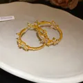 Detail of 18k gold plated hoop earrings featuring sparkling zircon butterfly motifs. - Gold
