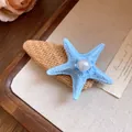 Close-up of a blue starfish hair clip with a pearl detail on a raffia woven base. - Duckbill Clip - Single Piece / Blue