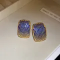 Detailed macro view of gold plated vintage C-shaped earrings with blue sparkling zircons - Blue