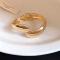Detailed close-up showing the metallic sheen of a minimalist gold twisted water drop bangle - Gold