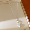 Close-up of a silver-tone necklace with a unique white pinecone and glass bead pendant - Silver-Hazelnut/Pinecone