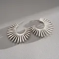 Close-up of silver-tone C-shaped hoop earrings with sunburst spike design details. - Silver Needle / Silver