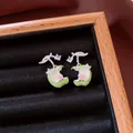 Macro view of green enamel apple stud earrings with pink flower and sparkling zircon accents. - Apple Shaped / Green