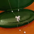 Detailed view of silver hollow bow necklace with pearls in a green jewelry box - Silver Hollow Bowknot Pearl Style (HN12570) / 1 Piece