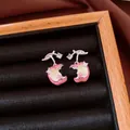 Close-up view of pink and yellow enamel apple stud earrings with shiny zircon accents in tray - Apple Shaped / Pink