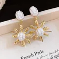 Close-up of French vintage gold earrings with textured pearl flower design - Gold